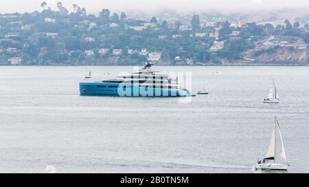 Eine Super-Yacht liegt in der San Fransico Bucht mit Hafengrundstück im Hintergrund. Aviva wurde von Sausalito an einem nebligen Augustmorgen genommen. Stockfoto