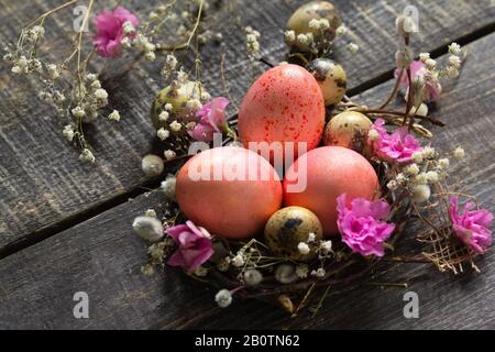 Osterhintergrund mit Pink handgefertigten Ostereiern und Frühlingsblumen. Stockfoto