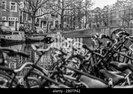 Fahrräder und Kanäle sind ein typischer Anblick von Amsterdam. Hausboote und Architektur aus dem 18. Jahrhundert säumen die Straßen von Wohngebieten. Stockfoto