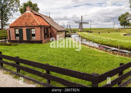 Zuiderzee Museum Enkhuizen. Malerisches holländisches Ferienhaus und Windmühle mit einem Boot am Bach. Stockfoto