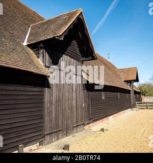 Old English Farm Barn. Das Äußere einer alten Holzscheune auf einem englischen Bauernhof in der hellen Frühlingssonne. Stockfoto