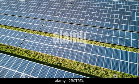 Solarfarm und Paneele. Reihen von Sonnenkollektoren, die an einem hellen sonnigen Tag eine abstrakte Hintergrundtextur mit vollem Rahmen von Blau und Grün erzeugen. Stockfoto