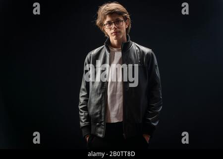 Gutaussehender Teenager in Lederjacke mit schwarzem Hintergrund Stockfoto