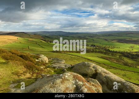 Landschaftlich schöner Blick von Embsay Crag (sonnenbeleuchtete Fells oder Moore, Bauernfelder im Tal, hohe Hügel, dramatischer Himmel) - North Yorkshire, England, Großbritannien. Stockfoto