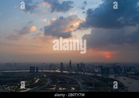 Dramatische Luftaufnahme des Saigon Flusses und der Skyline von Ho Chi Minh City bei Sonnenuntergang mit wunderschönen stürmischen und bunten Wolken am Himmel Stockfoto