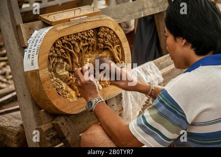 Asiatische handgefertigte Tische und Stühle in Möbelwerkstatt: Eine Touristenattraktion, die einzigartige, wiederverwendete Holzschnitzereien herstellt. Handgemeißelte Stücke, feine Handwerkskunst mit Tier- und Landschaftskunst für den Export, in Thailand: Eine Touristenattraktion, die einzigartige, wiederaufbereitete Holzschnitzel herstellt. Handgemeißelte Stücke, feine Handwerkskunst mit Tier- und Landschaftskunst für den Export nach Thailand, Großbritannien Stockfoto