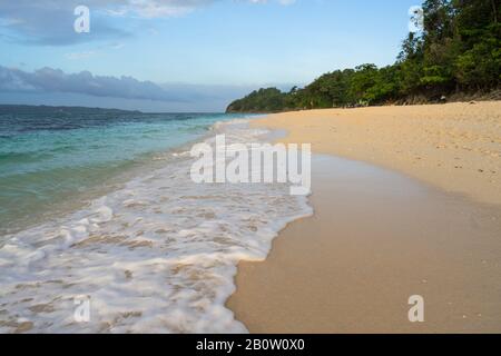 Wunderschöner Strand von Boracay Puka mit Meeresschaum aus Wasserwellen und blauem Wasser bei Sonnenuntergang Stockfoto