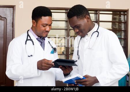 Junge Ärzte stehen und teilen Techniken der Arbeit an einem Tablet. Stockfoto