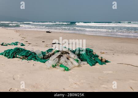 Plastikflaschen und anderer Müll, der auf die Sandküste geworfen wird, Müll am Meeresstrand, ökologisches Problem. Umweltverschmutzung. Schmutziger Sandstrände Stockfoto