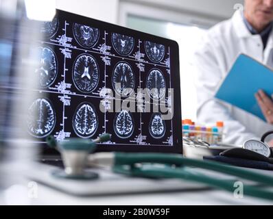 Nahaufnahme von Stethoskop und Gehirnscan auf einem Computerbildschirm, Wissenschaftler im Hintergrund. Stockfoto
