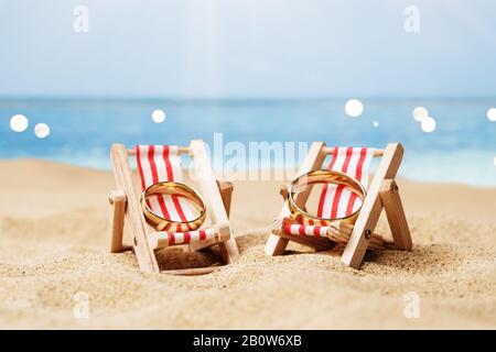 Goldene Und Glänzende Hochzeitsringe Auf Liegestühlen Auf Sand Am Strand Stockfoto