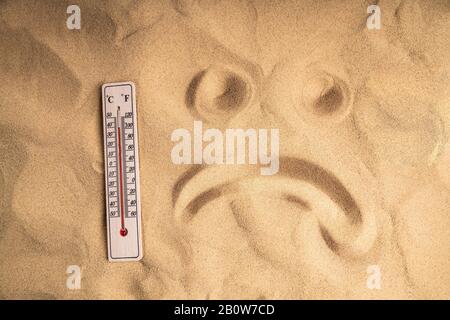 Nahaufnahme Des Thermometers Mit Hoher Temperatur Auf Sand Und Traurigem Gesicht Stockfoto