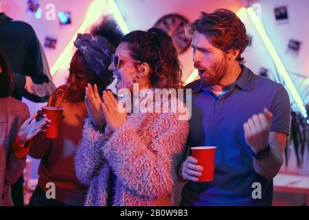 Eine Gruppe junger Leute, die mit Getränken aufgeregt waren und Spaß mit Freunden auf der Party hatten Stockfoto