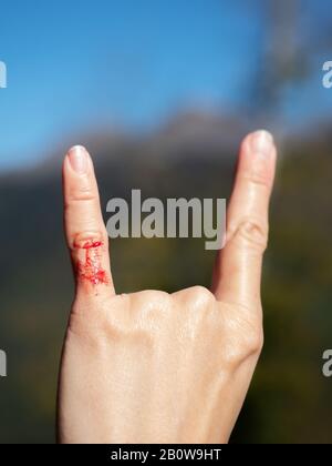 Nahaufnahme der Hand einer Frau mit zwei nach oben erhobenen Fingern, was auf einen Felsen hinweist und auf verschwommenem Hintergrund rollt Stockfoto