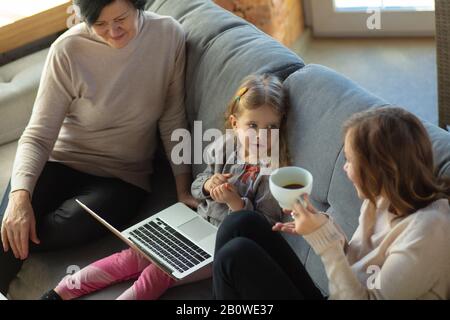 Glück. Glücklich liebende Familie. Großmutter, Mutter und Tochter verbringen gemeinsame Zeit. Kino ansehen, Laptop benutzen, lachen. Muttertag, Feier, Wochenende, Urlaub und Kinderkonzept. Stockfoto