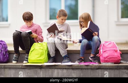 Kinder mit Rucksäcken stehen im Park in der Nähe von Schule Stockfoto