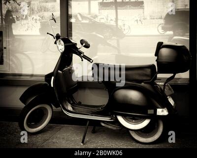 Vintage Black Italian Styl Roller mit weißen Wandreifen und seitlich angebrachtem Ersatzteil. Hinterer Kunststoff-Aufbewahrungskasten in schwarz-weißer Ausführung. Art Photo Stockfoto