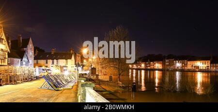 Bewdley, Großbritannien. Februar 2020. Wetter in Großbritannien: Ein beispielloses Flussniveau in Bewdley, Worcestershire, ruft dazu auf, dass lokale Notfalldienste zusammenarbeiten, um die Geschäfte und Einwohner der Stadt zu schützen. Auf beiden Seiten des River Severn in Bewdley sind in dieser Panorama-Stadt-Ansicht Überschwemmungsbarrieren zu sehen, während die nächtlichen Straßenbeleuchtung im aufgequollenen Flusswasser reflektiert. Kredit: Lee Hudson Stockfoto