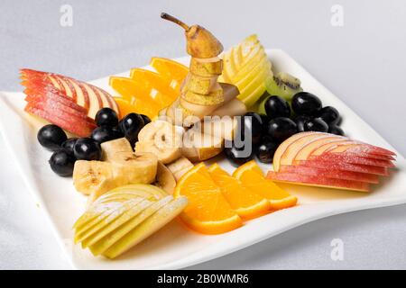 Schnitzfrucht-Konzept. Blick auf einen Obstsalat mit Erdbeeren, Orangen, Kiwi, Blaubeeren und Pfirsichen Stockfoto