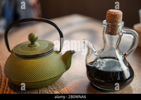 Grüne Teekanne auf dem Holztisch und Sojabecher am Tisch des Cafés Stockfoto