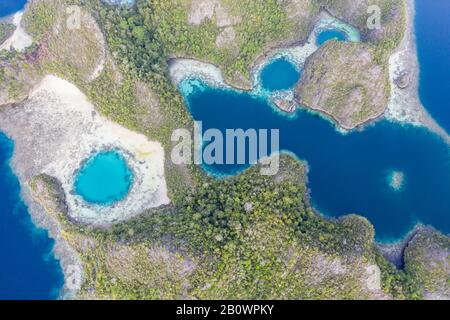 Zerklüftete Kalksteininseln ragen aus der heiteren Seescape in Raja Ampat, Indonesien auf. Diese tropische Region wird als Herz des Korallendreiecks bezeichnet. Stockfoto