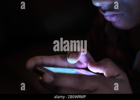 Nahaufnahme des jungen Mannes nutzen nachts das Smartphone Stockfoto