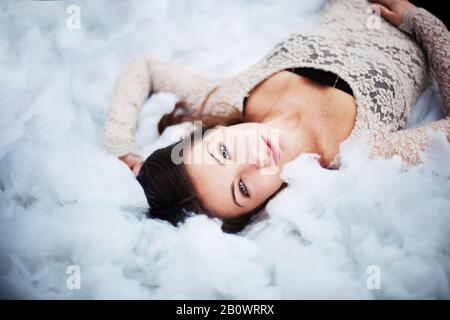 Junge Frau liegt auf Baumwollkugeln Stockfoto