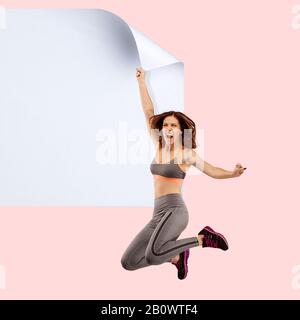 Stellen Sie sich vor, wer das weiße Blatt bedeckt, um das digitale Dateisymbol zu erhalten. Junge Sportlerin fängt den Rand eines riesigen Papierbogens ein. Digitale Welt, lustige Vorstellung von der Art und Weise, wie die Ikone erscheint. Stockfoto