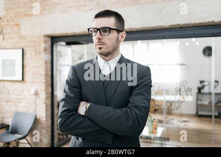 Erwachsener in elegantem Anzug und Brille. Selbstbewusster Geschäftsmann, der Brille trägt und mit den Händen im feigen Raum zusehen kann. Stockfoto