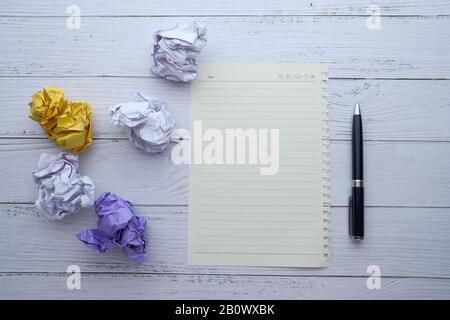 Draufsicht auf Knautschpapierkugel und Notizblock auf dem Tisch Stockfoto
