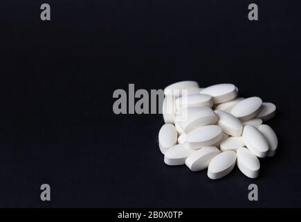Weiße Pillen auf schwarzem Hintergrund. Freier Speicherplatz. Medizinisches Konzept. Stockfoto