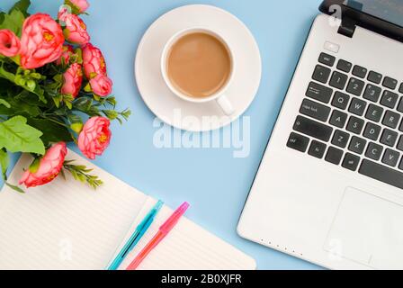 Weiße Tasse Kaffee-Notizblock, pinke Blume, Stifte, Laptop-Tastatur auf blauem Hintergrund. Flaches Layout. Kopierbereich. Draufsicht. Stockfoto