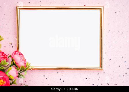Goldener Rahmen für Fotografie, Blumen, rosafarbener Hintergrund mit Glitzereffekt. Flach, lat. Draufsicht. Platz für Text Stockfoto