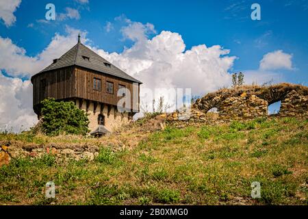Hartenstejn, Tschechien - 11. August 2018: Blick auf einen Steinturm als Teil einer im 15. Jahrhundert erbauten, zerstörten Burg auf einem grünen Hügel. Sonniger Tag. Stockfoto