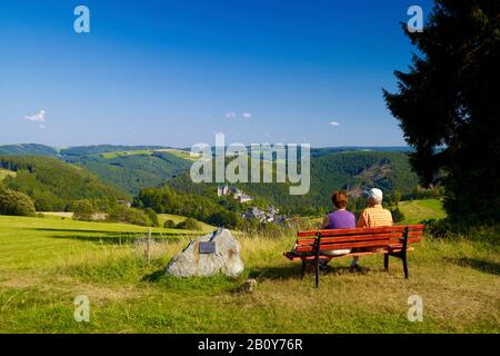 Wanderer auf einer Bank mit Blick auf Schloss Lauenstein und Ort bei Ludwigsstadt, Oberfranken, Bayern, Deutschland, Stockfoto