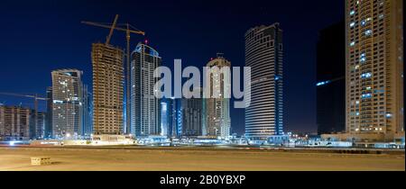 Wolkenkratzer und Sandgebiet in Jumeirah Lakes Towers (JLT) nachts, New Dubai, Vereinigte Arabische Emirate, Stockfoto