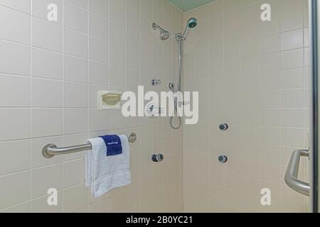 Geflieste Dusche mit Handtüchern und Handlauf Stockfoto