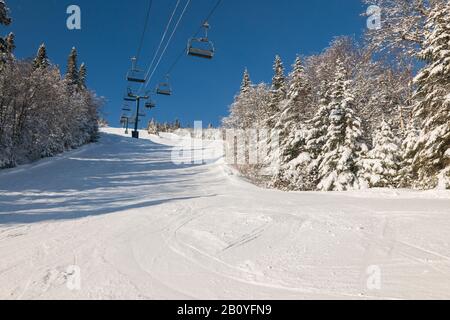 Blick auf die Skifahrer auf dem Skilift mit schneebedecktem Berg-Sesselbahn über der Skipiste Stockfoto