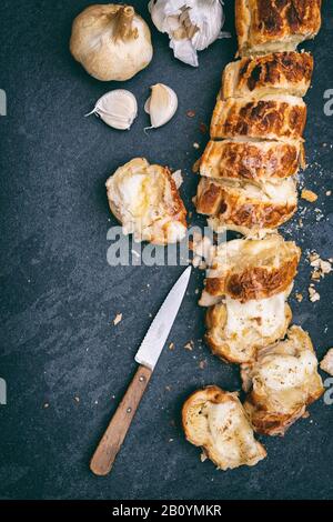 Hausgemachtes Knoblauchbrot und geschmolzener Käse auf Schiefergrund Stockfoto