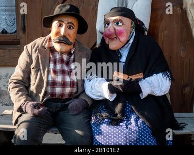 Maskiertes Paar nimmt am Karneval Teil.Traditioneller Karneval in Sappada, einer deutschsprachigen Stadt in den Dolmiti-Bergen in Italien, wo die Menschen immer noch ihren altmodischen deutschen Mundart verwenden, ist in drei Sonntage unterteilt: Sonntag der Armen, Sonntag der Bauern und Sonntag der Herren. Die Menschen tragen traditionelle Holzmasken namens "Love" und spielen lustige Charaktere, um Nachbarn und Besucher zu unterhalten. Die wichtigste Maske ist Rollat, ein riesiger Mann in Schaftfellmantel mit Holzgesicht des Hirten. Stockfoto