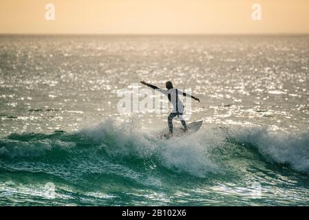 Surfer bei Sonnenuntergang, Big Bay, Kapstadt, Südafrika Stockfoto