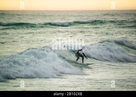 Surfer bei Sonnenuntergang, Big Bay, Kapstadt, Südafrika Stockfoto