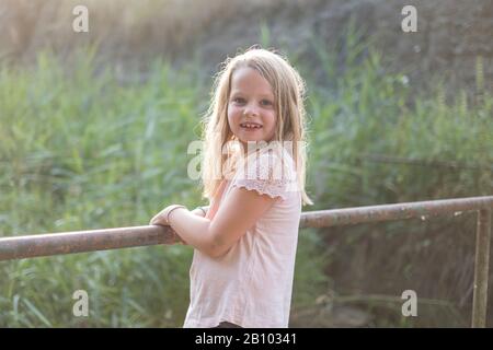 Kleines Mädchen steht auf einer Brücke an einem Fluss Stockfoto