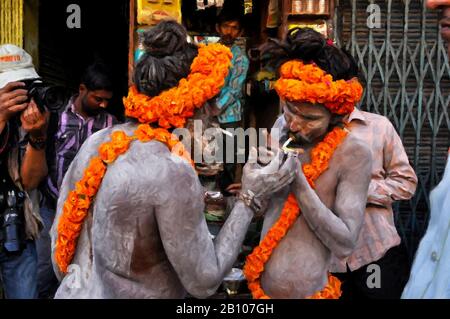 Digitale Gemälde: Naga Sadhu-12 Digitales Gemälde von zwei Naga Sadhus mit einer Adresse von marigalten Blumen, die Zigarette in Varanasi, Indien, säumen. Stockfoto