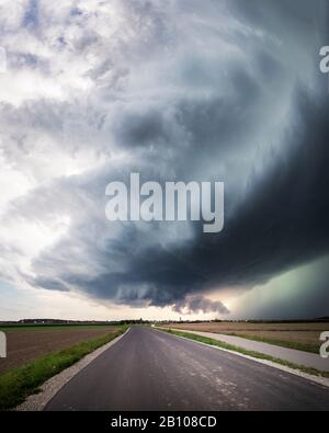 Panorama einer Superzelle mit tief liegender Wandwolke, gesundem Windfuß und glühendem grünem Niederschlagskern über einer Landstraße bei Heilsbronn, Bayern, Deutschland Stockfoto