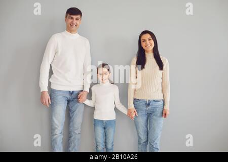 Fröhliche Familie lächelt, während sie vor grauem Hintergrund steht. Stockfoto