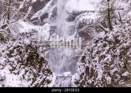 Multnomah Falls, Oregon USA - 10. Februar 2019: Blick auf eine malerische Brücke vor einem Wasserfall, der im Schnee liegt Stockfoto