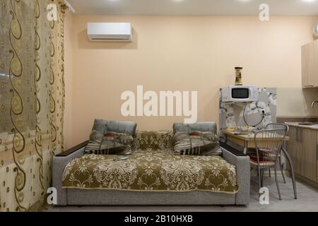 Fragment des Innenraums der Studio-Wohnung, neben dem Sofa befindet sich ein Esstisch Stockfoto