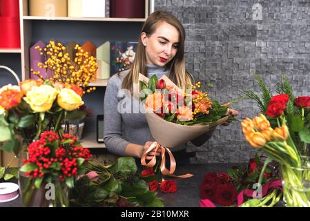 Mädchen sammelt einen Blumenstrauß verschiedener Blumen. Kleine Unternehmen. Stockfoto