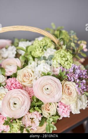 Blumen Lieferung. Blumenarrangement im großen Korbkorb. Wunderschöner Blumenstrauß aus gemischten Blumen in der Hand der Frau. Blumengeschäft Konzept . Schön frisch Stockfoto